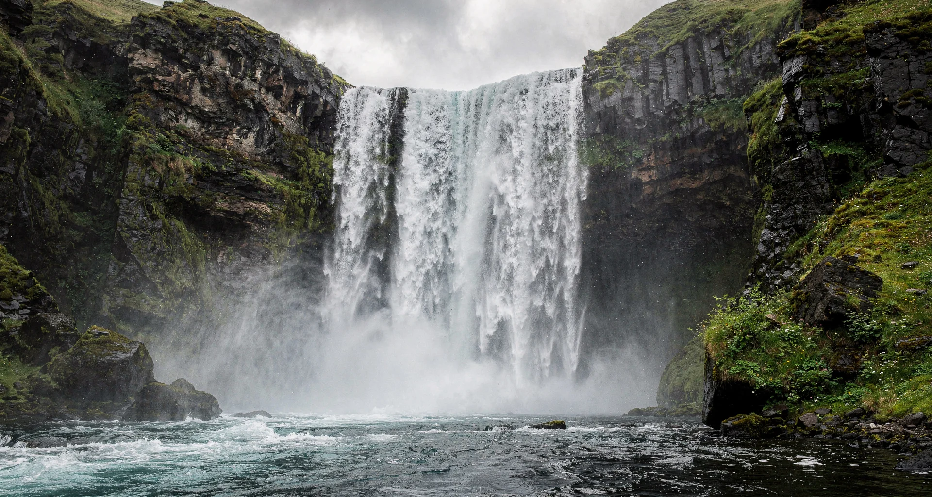 Skogafoss waterfall cascading down basalt cliffs surrounded by deep atmospheric fog